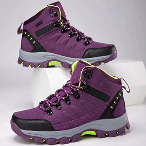 Zwei Paar violette wasserdichte Wanderschuhe mit neongrünen Akzenten auf weißen Podestblöcken