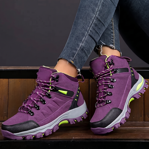 Nahaufnahme violetter wasserdichter Wanderschuhe mit neongrünen Akzenten, an Jeans getragen
