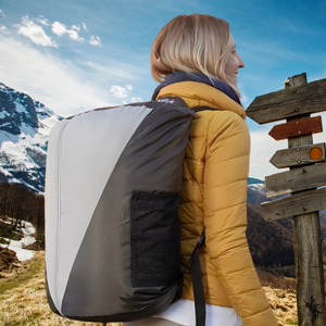 Wanderin trägt den zusammengepackten Camping-Schlafsack als Rucksack in den Bergen